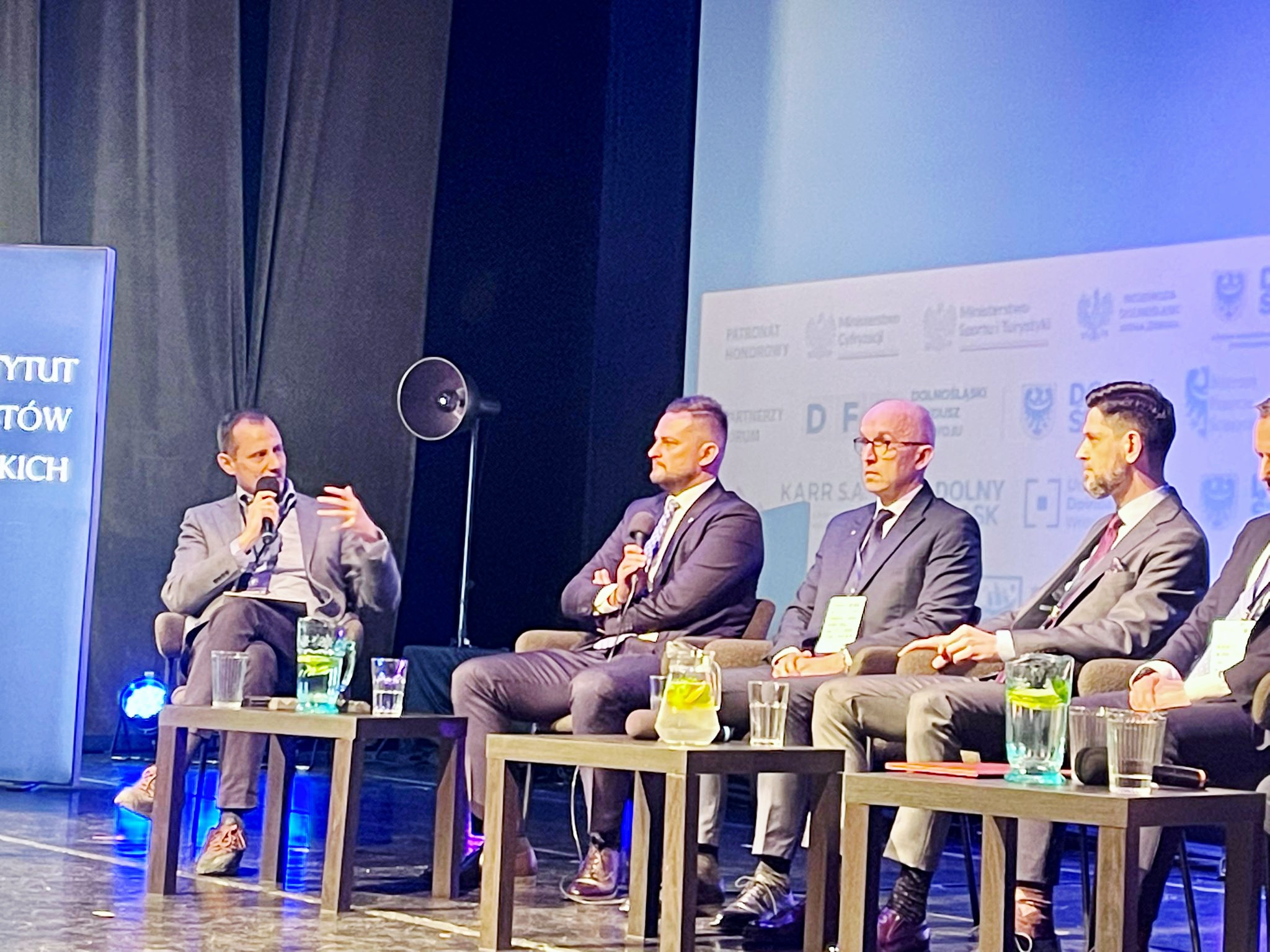 Zbliżenie na panelistów rozmowy o innowacjach Dolnego Śląska. Na zdjęciu widać moderatora Łukasza Czajkowskiego oraz Michała Rado - Wicemarszałek Województwa Dolnoślaśkiego